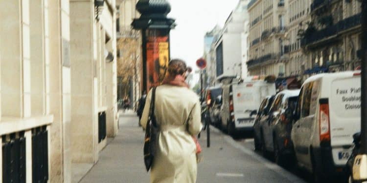 a woman walking down a street next to parked cars