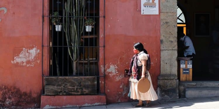 a woman walking down a street past a red building